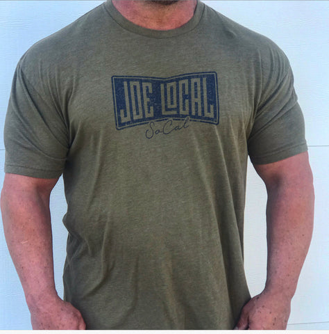 Front of the t-shirt. Military green t-shirt with navy blue Joe Local So Cal flag logo at the center of the chest. Well-fitted and comfortable t-shirt. Fabric: CVC Jersey 60% Combed Ring-Spun Cotton 40% Polyester /32 singles, 145 grams/4.3 oz Neck: Crew