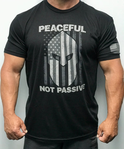 60% Cotton, 40% Poly. Black Crew neck. shirt has a large screen print in white. logo is of a warrior helmet layered over and American flag. phrase “Peaceful Not Passive. The word “peaceful” is located at top of the flag/helmet and the words “not passive” is featured at bottom of the flag/helmet. back of the t-shirt features small simple “Joe Local” logo across top of t-shirt under the neck. left sleeve features a small screen print of the American flag in white.